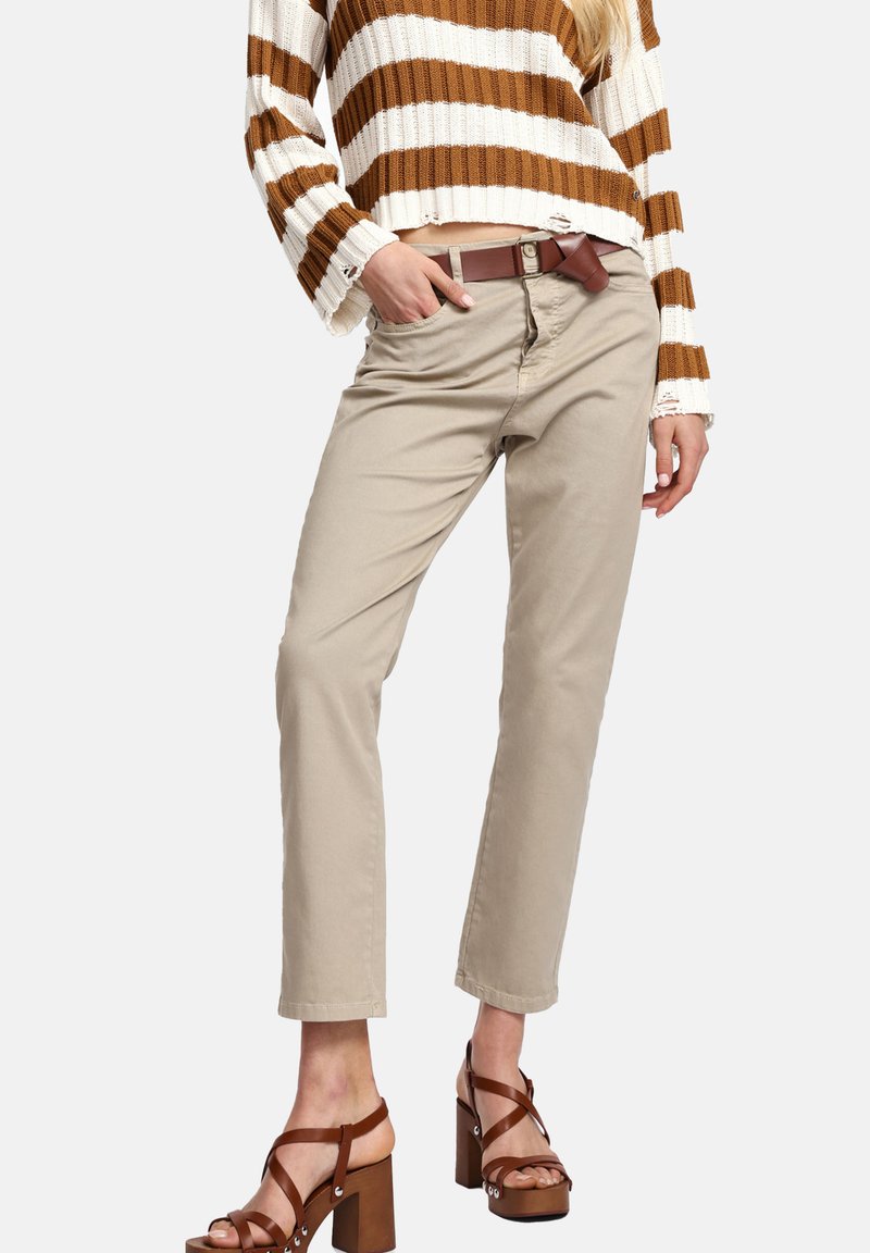 Pantaloni beige a gamba dritta con una tasca frontale e una cintura marrone. Abbinati a un maglione corto a righe marroni e bianche e a tacchi a blocco marroni.