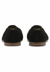 Černé semišové slip-on boty s plochou podrážkou, na zadní straně s malým logem TOMS a hladkým, minimalistickým designem.