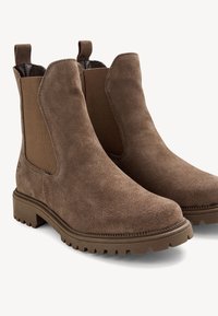 Bottes Chelsea en daim marron avec panneaux latéraux élastiques, semelles en caoutchouc robustes et languettes à tirer ; bout arrondi et coutures détaillées.