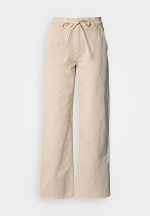 Pantalon large beige en coton, doté d'une taille à cordon, d'une texture lisse et de détails de couture simples.
