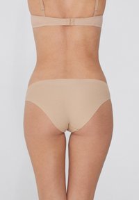 Beige nahtlose Unterwäsche mit glatter Textur und niedrig geschnittenem Design, das leichte elastische Akzente am Bund und den Beinöffnungen aufweist.