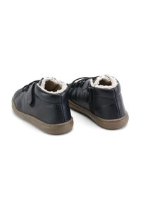 Botas de tobillo de cuero negro con un forro de pelusa, parte delantera con cordones, cremallera lateral y suelas de goma texturizada. Forma redondeada con un acabado suave.