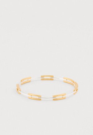 Hõbe- ja kuldne käevõru, millel on omavahel ühendatud segmendid, sile pind ning minimalistlik disain kontrastsete värvide ja metallaktsentidega.