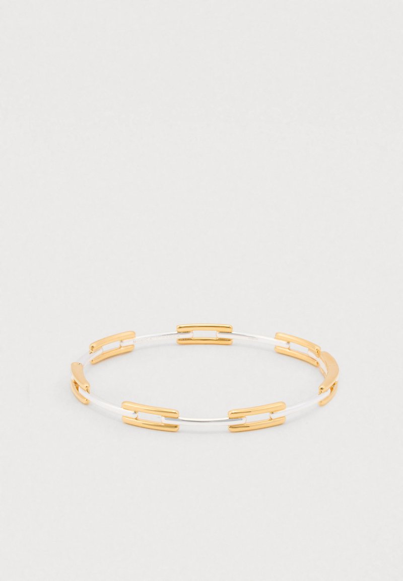 Silver and gold bracelet featuring interlocking segments, a smooth surface, and a minimalist design with contrasting colors and metallic accents.