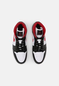 Dvojice černých, bílých a červených tenisek Nike Air Jordan z pohledu shora na bílém pozadí.