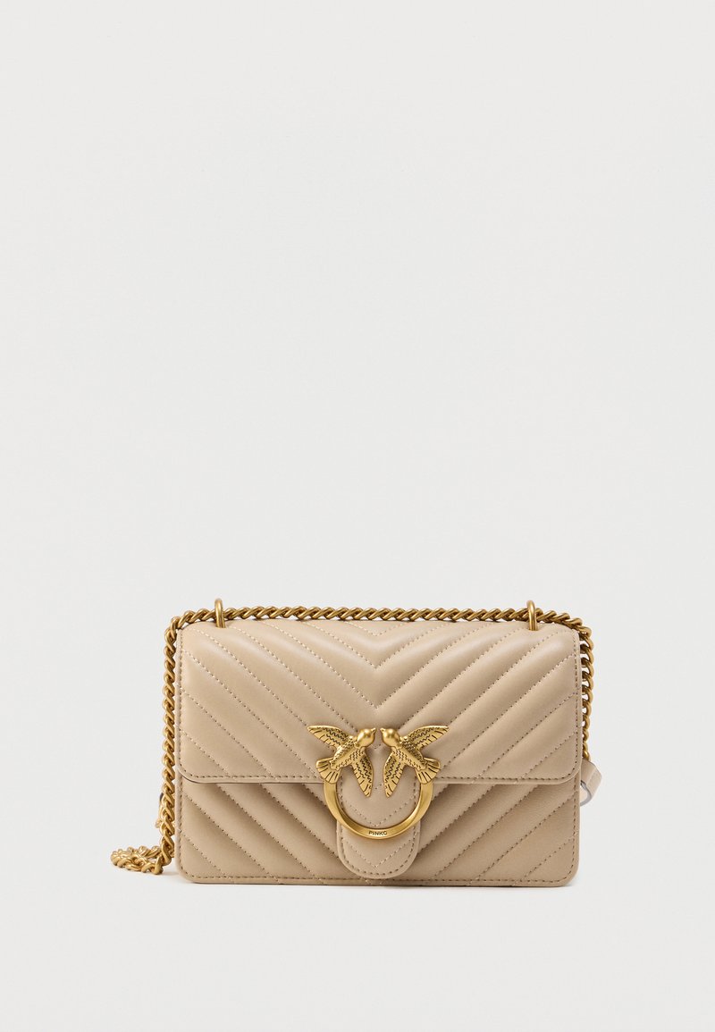 Geantă de mână din piele bej matlasată, cu o curea lanț aurie, având o închizătoare rotundă proeminentă decorată cu doi păsări.