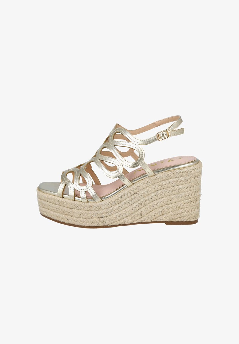 Sandalia cuña metálica dorada con textura de cuerda trenzada. El diseño abierto en la parte delantera presenta patrones recortados y una correa en el tobillo ajustable.