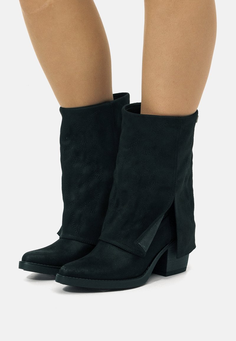 Botas de ante negras a la altura del tobillo con un diseño plisado, punta afilada y tacón de bloque. Acentos de aberturas laterales notables que realzan el interés visual.