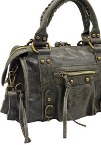 Sac à main en cuir gris avec une finition texturée, une anse tressée, des accents en or, plusieurs fermetures éclair et des clous décoratifs sur les côtés.