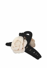 Svart hårklämma med en krämfärgad filtblomma. Klämman har en texturerad yta med randiga accenter och en blommig design.
