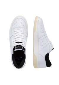 Sneakers bianchi in pelle sintetica con dettagli perforati, lacci piatti e un accento nero sul tallone. Suola color crema.