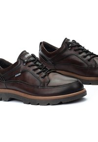 Zapatos de cuero marrón con cordones, acabado texturizado, suela de goma y detalles de costura. Cuentan con un interior acolchado y lengüeta reforzada.