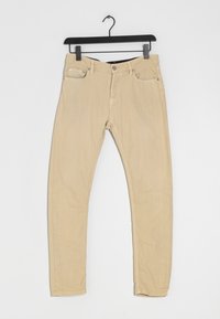 Jean beige en coton extensible avec une coupe slim, cinq poches et des accessoires métalliques. Le tissu présente une texture lisse et une couleur neutre.