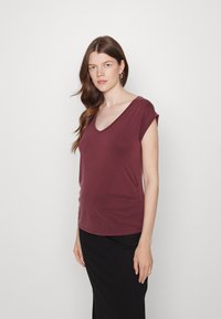 Top cortado bordô de mangas curtas com um decote em V profundo e detalhes de franzido na lateral, feito de tecido suave, combinado com uma saia preta.