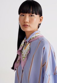 Svetlomodrá pruhovaná košeľa s jemnou textúrou, s multicolor vzorovaným hodvábnym šálom zviazaným pri golieri.