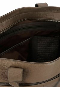 Interieur van een bruine leren tas met een gestructureerde afwerking, een ritsvak en een gladde voering. Bevat extra vakken voor organisatie.