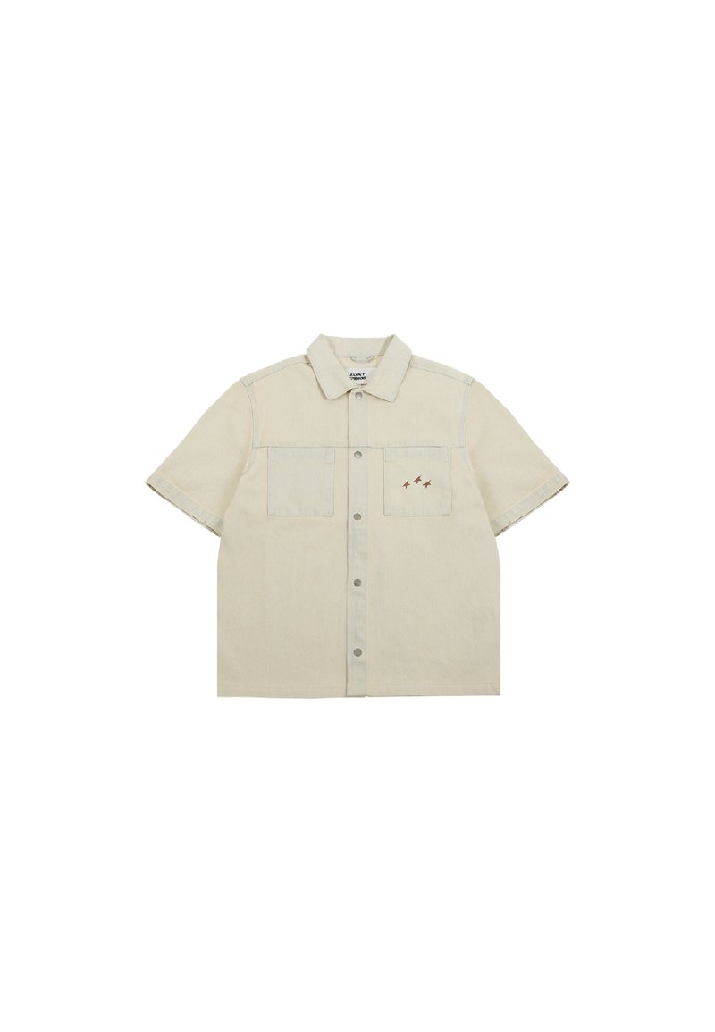 Chemise en denim beige à manches courtes avec un devant à boutons, deux poches poitrine et des accents brodés en marron. Présente des coutures contrastées.