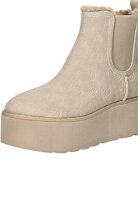 Stivale alla caviglia con plateau beige realizzato in materiale testurizzato con fodera in pelliccia. Presenta pannelli laterali elasticizzati e una silhouette a punta rotonda.