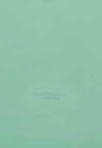 Grønn læretote med preget logo. Glatt tekstur, strukturert form, har minimalistisk design og ingen synlig maskinvare.