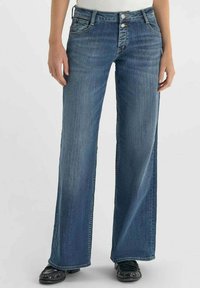 Jean large bleu foncé en denim. Doté d'une fermeture à boutons, de cinq poches et d'un léger délavage à l'avant, se positionnant à la taille.