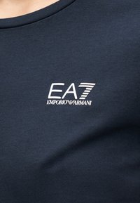 Donkerblauw katoenen T-shirt met een ronde hals en het EA7 Emporio Armani-logo in het wit, met een gladde textuur.