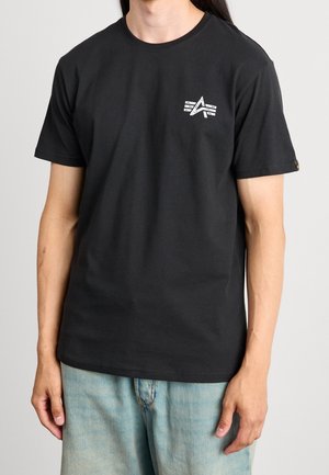 Sort bomuld t-shirt med korte ærmer, med en lille logo på brystet. Kombineret med lyseblå denimshorts.