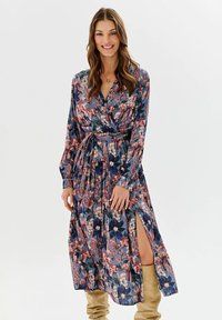 Rochie tip petrecută cu imprimeu floral în albastru închis, cu flori roz și albe. Mâneci lungi și detaliu cu tăietură laterală. Țesătură moale, cu textură fină.