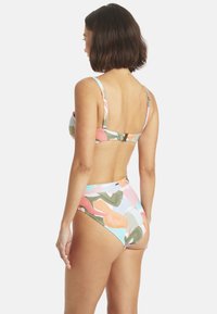 Bikini deux pièces avec un motif floral abstrait, présentant des couleurs pastel telles que le rose, le vert et le bleu. Le haut est doté de bretelles ajustables et d'une fermeture à clip.