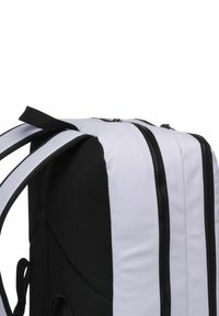 Mochila en blanco y negro con una tela texturizada, doble cremallera y correas de hombro acolchadas para mayor comodidad.
