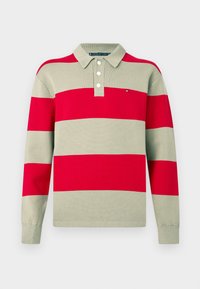 Polo majica z dolgimi rokavi, ki ima izmenično rdeče in bež vodoravne črte, troje gumbov ob izrezu ter majhen logotip na prsih.