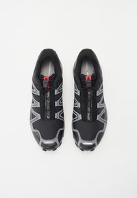 Black athletic shoes with grey accents, mesh upper, contoured shape, quick lace system, and textured soles designed for grip.