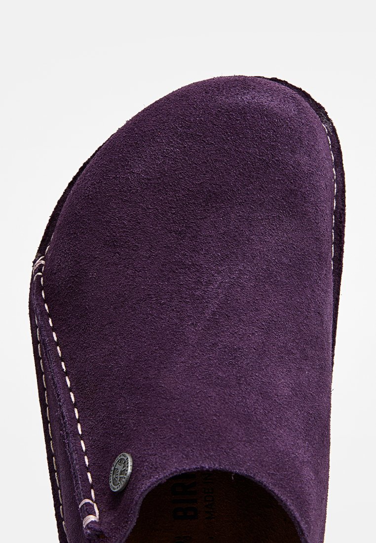 Lila Wildlederschuh zum Hineinschlüpfen mit runder Zehenpartie, kontrastierender Naht und einem kleinen Metalllogo-Detail an der Seite. Flache Sohle.