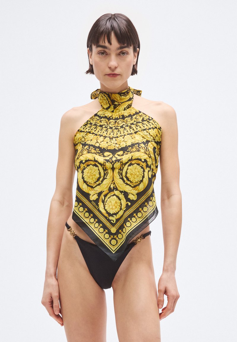 Črni bikini spodnji del iz blaga z zlato poudarjenimi okraski, kombiniran s rumeno-črnim vzorčastim zgornjim delom s halter ovratnikom. Podroben cvetlični dizajn.