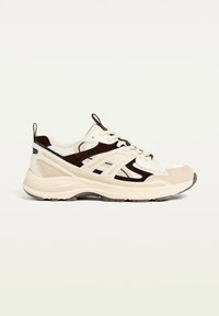 Beige and brown athletic shoe, featuring mesh fabric, textured overlays, round toe, and cushioned sole with contrasting accents.