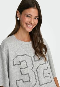 Szara, oversize T-shirt z dużym czarnym wzorem "32" ozdobionym dżetami, z okrągłym dekoltem i krótkimi rękawami.