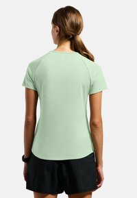 Light green short-sleeve t-shirt with a curved hemline and raglan sleeves, made from a smooth, lightweight fabric.