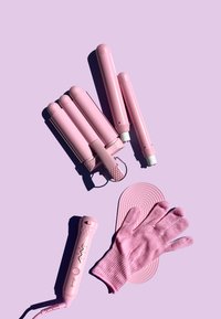 Pięć różowych narzędzi do stylizacji włosów, w tym lokówka i rękawica odporna na wysoką temperaturę, wyeksponowanych na miękkim różowym tle z teksturowymi akcentami.