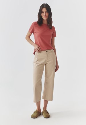 Pink short-sleeve t-shirt paired with beige wide-leg pants and olive green clogs. Smooth fabric with a relaxed fit and simple design.
