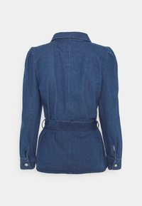 Veste en denim bleu foncé avec manches longues, poignets boutonnés, col et ceinture en tissu assorti à la taille, vue de dos.