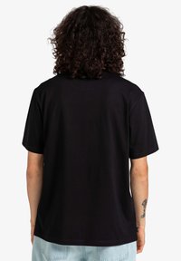 Camiseta corta negra de manga corta con un ajuste relajado, fabricada en material de algodón. Presenta un diseño simple, sin logotipos ni acentos visibles.