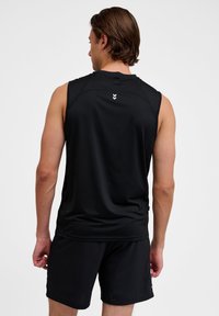 Zwarte mouwloze sporttop gemaakt van lichtgewicht stof met een gladde textuur, met een wit logo boven de achterkant van de halslijn.