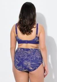 Set bikini viola con un motivo floreale e architettonico. Il reggiseno presenta spalline regolabili e chiusura a gancio. Slip a vita alta.