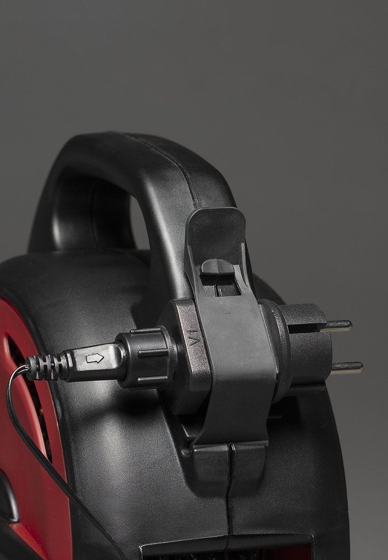 Herramienta eléctrica negra y roja con un mango redondo, equipada con un cable de alimentación y enchufe, textura suave y un conector asegurado.