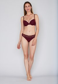 Burgundy bra with smooth, molded cups and thin straps, paired with matching lace-accents thong featuring a floral pattern at the waistband.