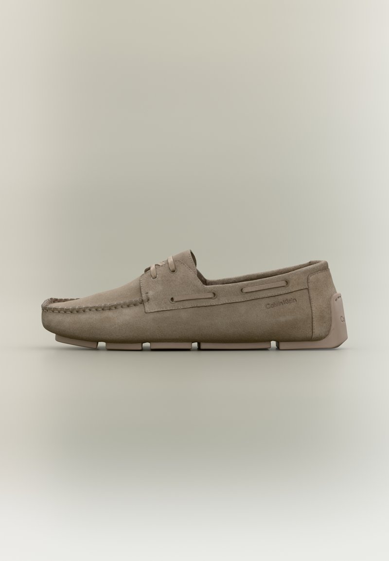 Mocassin en daim beige avec couture moc toe, détail lacet, semelle segmentée et logo Calvin Klein sur le côté et la languette du talon.