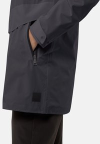 Giacca impermeabile grigia con tasca laterale con zip, orlo curvo e un'etichetta in tessuto in basso a sinistra. Tessuto liscio e design aderente.