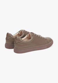 Brązowe skórzane sneakersy z zaokrąglonym noskiem, płaskimi sznurowadłami i teksturowaną gumową podeszwą. Minimalistyczny design z gładkim, matowym wykończeniem.