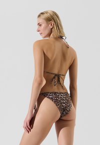 Bikini im Leopardenmuster mit Halterneck, verstellbaren Bindebändern und einem tiefen Bund. Glattes Material mit glänzendem Finish.