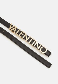 Cintura in pelle nera con una prominente fibbia in metallo dorato con la scritta "VALENTINO", dal design minimalista e una texture liscia.