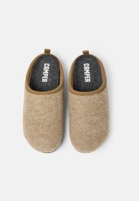 Beige felt slippers with a rounded shape, soft texture, and brown fabric trim. Features a dark grey insole with "CAMPER" branding.